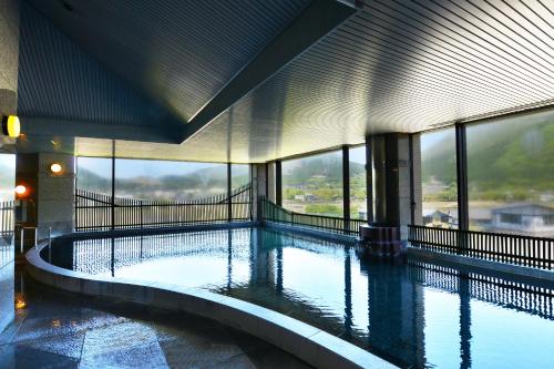 由布市汤布院秀峰馆酒店的一座大型游泳池,位于一座带窗户的建筑内
