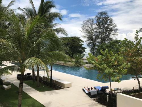 峇都丁宜By The Sea - UBTS SMART ENTERPRISE的棕榈树泳池和沙发上的人