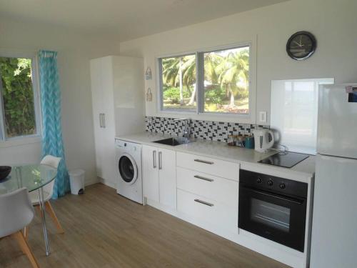 拉罗汤加Absolute Beachfront - A Slice of Paradise!的白色的厨房配有冰箱和洗碗机。