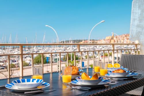 芒通La Grande Palmeraie - Spacieux studio avec vue mer, terrasse, port de Garavan的餐桌,带食物盘和橙汁杯