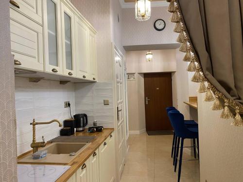 克拉科夫Radiance Residence的厨房配有白色橱柜、水槽和蓝色椅子