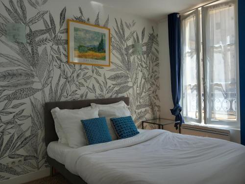 凡尔赛Le Studio Versaillais的一间卧室配有一张带蓝色和白色枕头的床