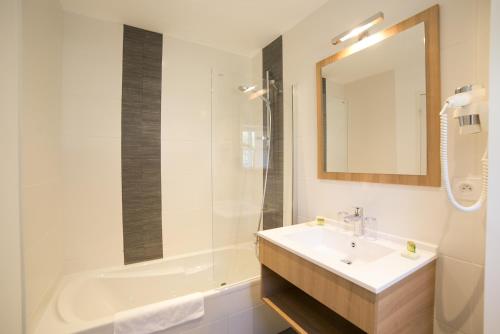 卡纳克安提根酒店的一间带水槽、浴缸和镜子的浴室