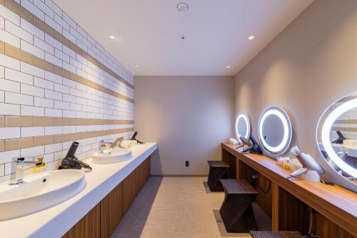 大阪Via Inn Prime Osaka Kyobashi的浴室设有3个水槽和墙上的镜子