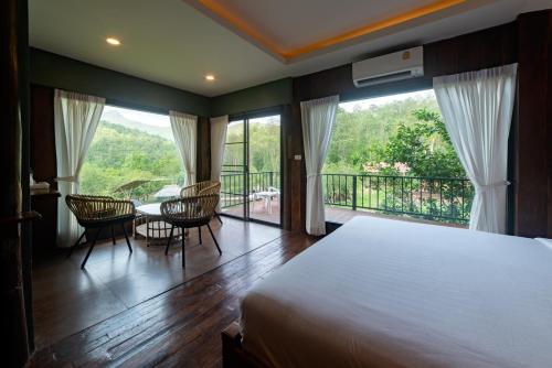 湄旺Tawan Riverside的一间卧室配有一张床,阳台配有桌椅