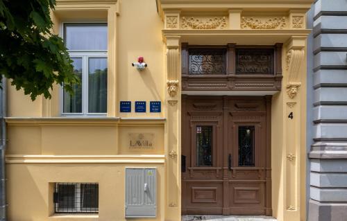 奥西耶克LAVilla Osijek的黄色的建筑,设有棕色的门和窗户