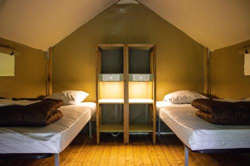 圣吉隆Camping Parc d'Audinac Les Bains的帐篷内带两张床的房间