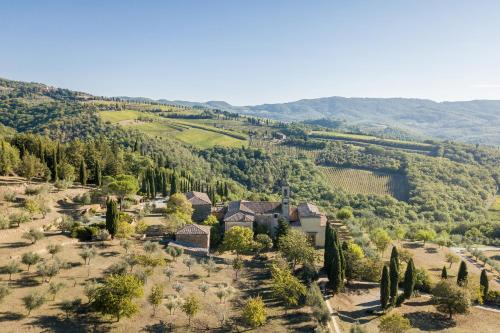 拉达-因基安蒂Pieve Aldina Relais & Châteaux的享有山谷中树木繁茂的房屋的空中景致