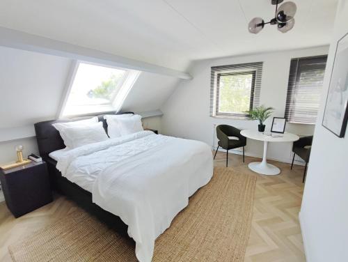 阿姆斯特尔芬Guesthouse at the Amstel river with 2BR 2BA and garden的卧室配有一张白色大床和一张书桌