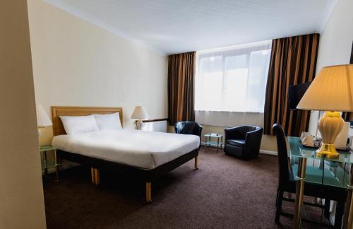 曼彻斯特曼彻斯特市中心大不列颠酒店的酒店客房设有一张床铺和一张玻璃桌