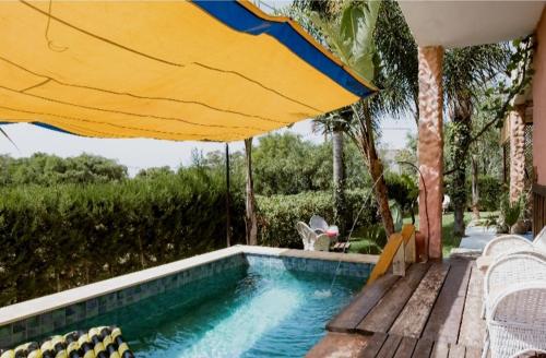 丹吉尔Hajrienne guest house的一个带遮阳伞和椅子的游泳池以及一个游泳池