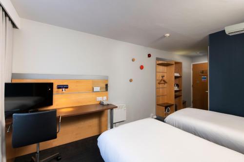 利兹利兹市中心智选假日酒店的一间卧室配有两张床和一张书桌及电视