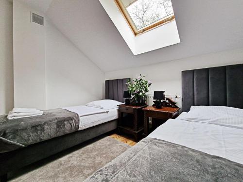 JasionkaKarczma Ostoya的一间卧室配有两张床、一张书桌和天窗。