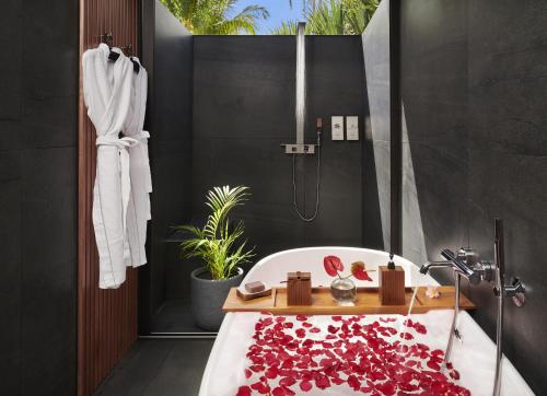 珀蒂蒂勒Palm Hotel & Spa的浴室配有浴缸,并覆盖着红色的花瓣