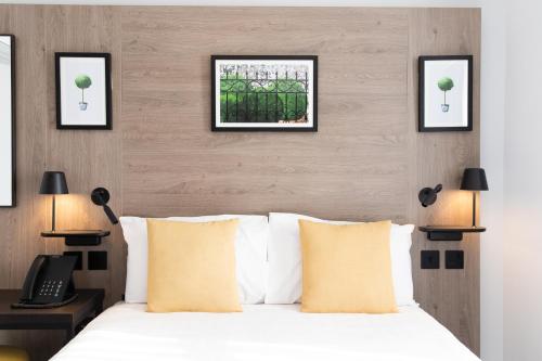 伦敦王子广场旅馆的卧室配有一张床,墙上有三幅照片