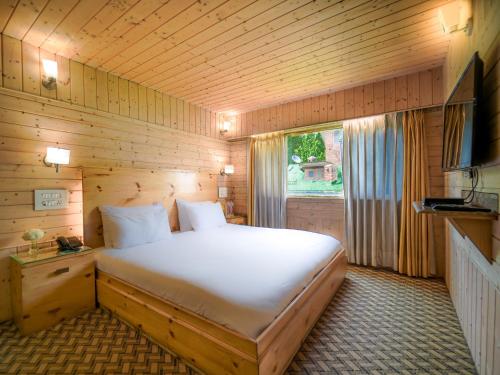 斯利那加幻影酒店的一间卧室设有一张大床和一个窗户。