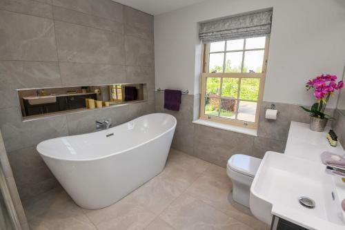Kirkby on BainSunset View at The Dovecote的浴室配有白色浴缸和卫生间。