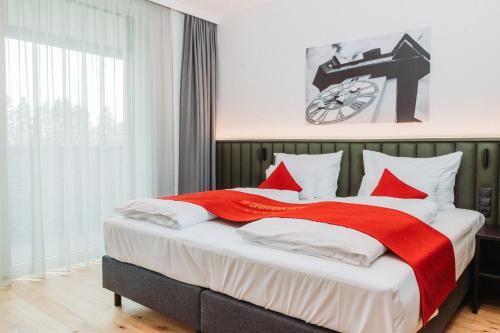 Hotel Das Grambacher的一间卧室配有一张带红色和白色枕头的大床