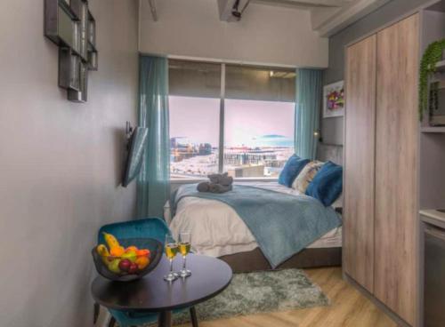 开普敦Executive City Micro Living in Long Street at One Thibault的一间卧室配有一张床、一张桌子和一个窗户。