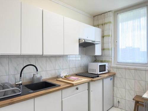 华沙Apartament Bazyliańska - 100m do Metra "Bródno", 20 minut do centrum Warszawy的厨房配有白色橱柜、水槽和微波炉
