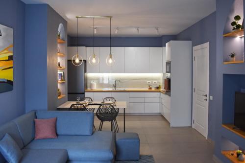 地拉那Vibrant Apartment的客厅以及带蓝色墙壁和蓝色沙发的厨房。