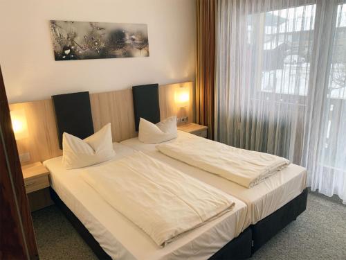因泽尔基姆高公寓酒店的一间卧室配有一张带白色床单的床和一扇窗户。