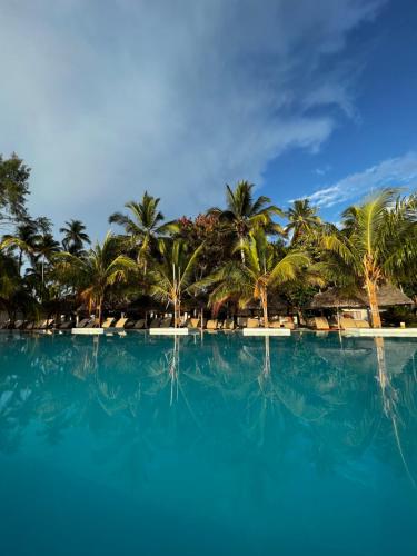 帕杰NDAME Paje Hotel的棕榈树和蓝色海水游泳池