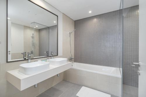 迪拜Upscale Two Bedroom with Balcony & Free Parking near Zabeel Park by Sojo Stay的浴室设有2个水槽、浴缸和镜子