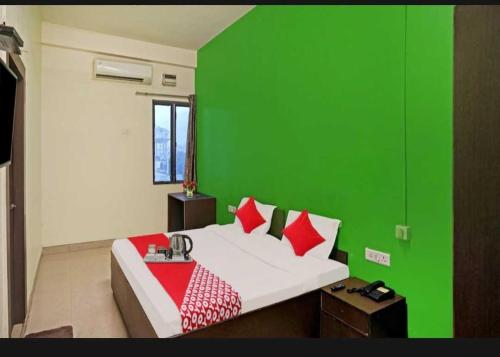 巴特那Flagship Hotel Heaven的绿色的围墙卧室配有一张带红色枕头的床