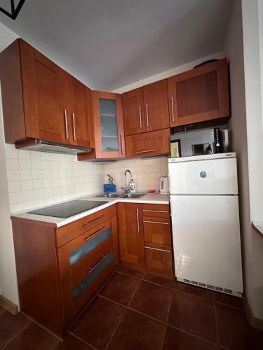 米兹多洛杰Apartament Międzyzdroje z widokiem na morze的厨房配有木制橱柜和白色冰箱。