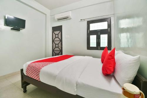 科塔Flagship Hotel Bliss的一间卧室配有一张带红色枕头的床和电视。
