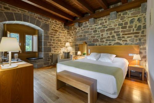 UrizHotel Rural Torre de Úriz的一间卧室设有一张床和石墙