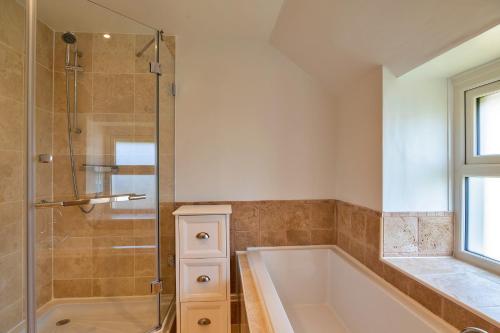 CarnbreaFinest Retreats - Trethew Cottage的带浴缸和玻璃淋浴间的浴室。