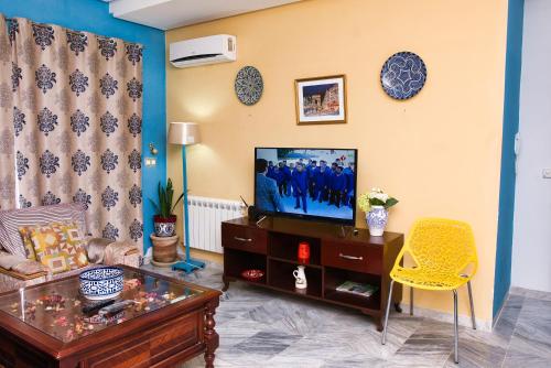 苏塞The Pearl Apartment Hammam Sousse WIFI的客厅配有电视和黄色椅子