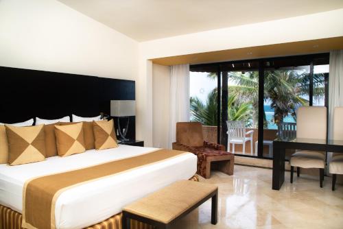 艾库玛尔Grand Oasis Tulum Riviera - All Inclusive的酒店客房设有一张床、一张书桌和一个阳台。