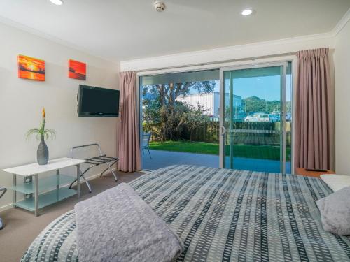 怀蒂昂格Marinaview - Whitianga Holiday Apartment的一间卧室设有一张床和一个滑动玻璃门