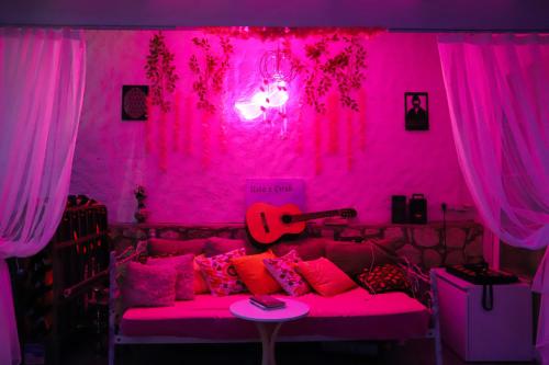 伊兹密尔Usta x Çırak Butik Otel的粉红色的房间,配有一张带吉他的床