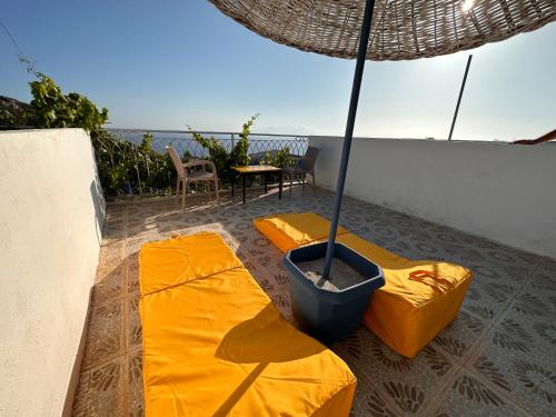 达特恰Goknar Knidos Oasis Nature Hotel的天井配有2张黄色垫子和遮阳伞