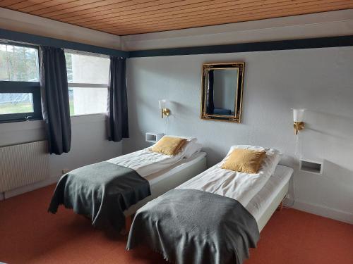 RendalenØiseth Hotell AS的配有镜子和窗户的客房内的两张床