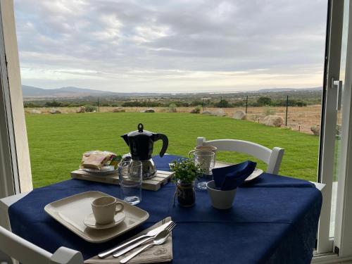 特乌拉达Is Arenas Biancas Agriturismo的一张带蓝色桌布的桌子,享有田野的景色