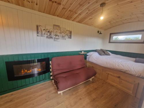 阿伯加文尼Cwtch Glamping Shepherds Huts的一间卧室配有一张床、一把椅子和一个壁炉