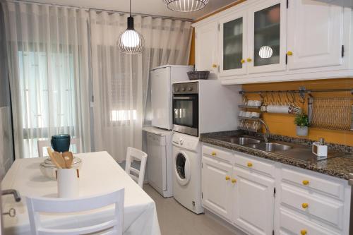 CaldelasCasa das Caldas的厨房配有白色橱柜、桌子和水槽。