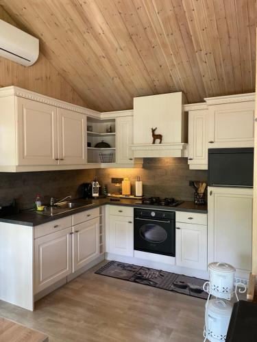 聚滕达尔Chalet Sint-Hubertus Deluxe的厨房配有白色橱柜和黑炉。