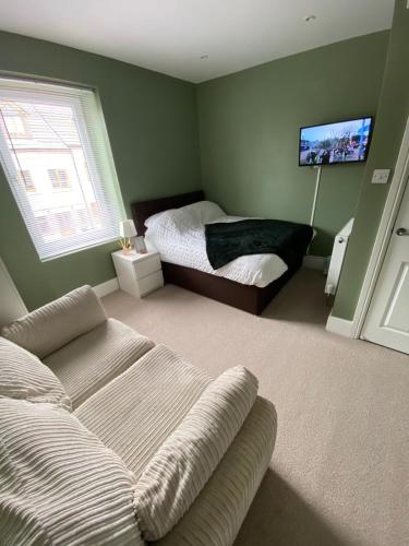 巴恩斯利Modern En-Suite Rooms Town Centre Self-Check In的一间卧室配有一张床、一张沙发和一台电视。