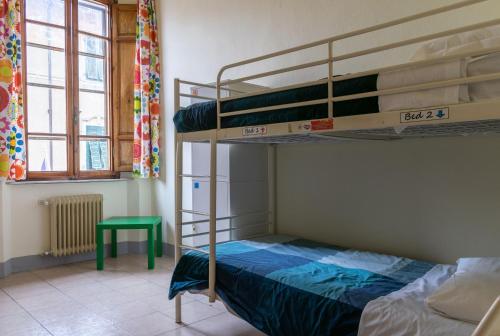 比萨比萨斜塔旅馆的一间卧室设有两张双层床和一张绿桌