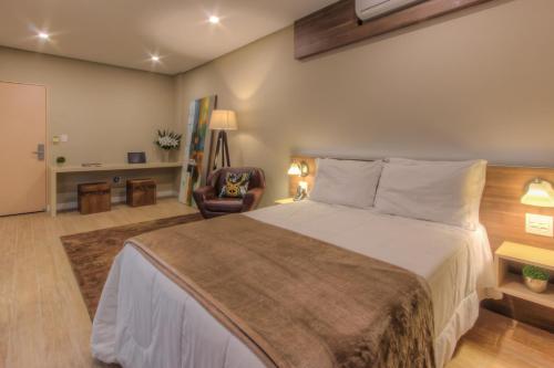 拉热阿杜Tri Hotel Lajeado的一间卧室配有一张大床和一把椅子
