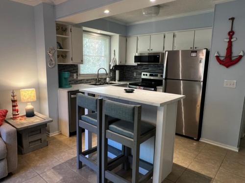 默特尔比奇C Level Condo的厨房配有冰箱和带两个吧台凳的吧台