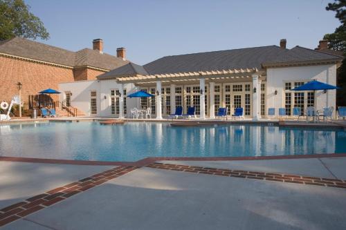 威廉斯堡威廉斯堡旅馆傲途格精选酒店 的一座带蓝色椅子的大型游泳池和一座建筑