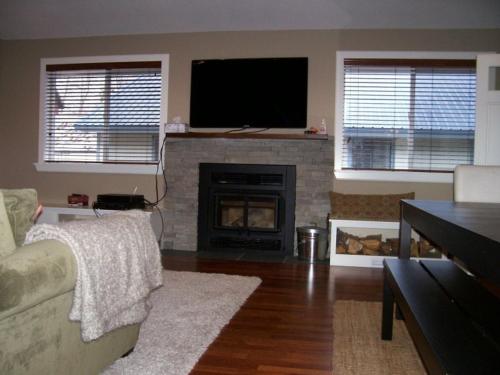 六月湖Elk House的客厅设有壁炉和平面电视