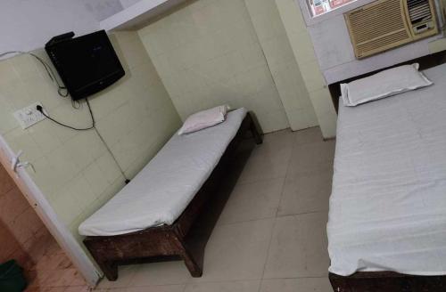 巴特那OYO Swaraj Guest House的客房设有两张床和一台墙上的电视。